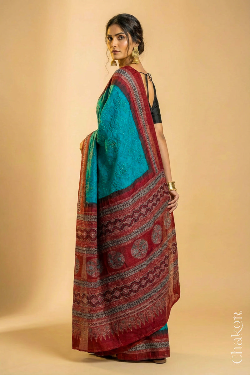 Woman wearing Peacock Blue Bandhani Saree with Natural Red Ajrakh printed border and pallu in pure gaji silk with traditional bandhej tie-dye, handcrafted in Kutch.