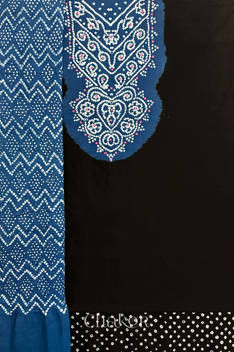 A black kurta set fabric with intricate bandhani & mirror embroidered contrast yoke, paired with a matching bottom & contrast indigo blue odhani placed on the left side featuring a zigzag design.