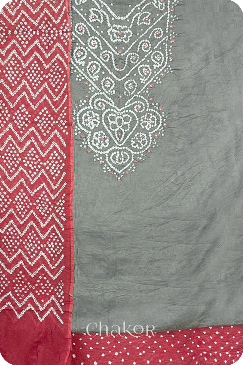 A grey kurta set fabric with intricate white bandhani & mirror embroidery, paired with a dusty red bottom & odhani featuring a zigzag design.
