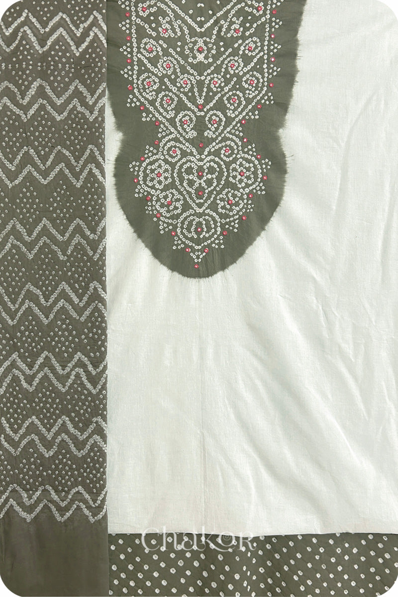 A grey- white kurta set fabric with intricate bandhani & mirror embroidery, paired with a grey bottom & odhani featuring a zigzag design.