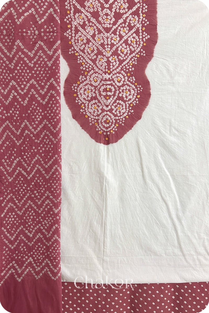 A soft rose pink- white kurta set fabric with intricate bandhani & mirror embroidery, paired with a soft rose pink bottom & odhani featuring a zigzag design.