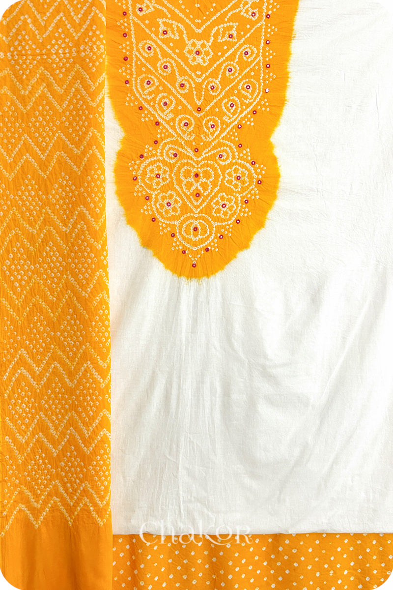 A yellow- white kurta set fabric with intricate bandhani & mirror embroidery, paired with a yellow bottom & odhani featuring a zigzag design.