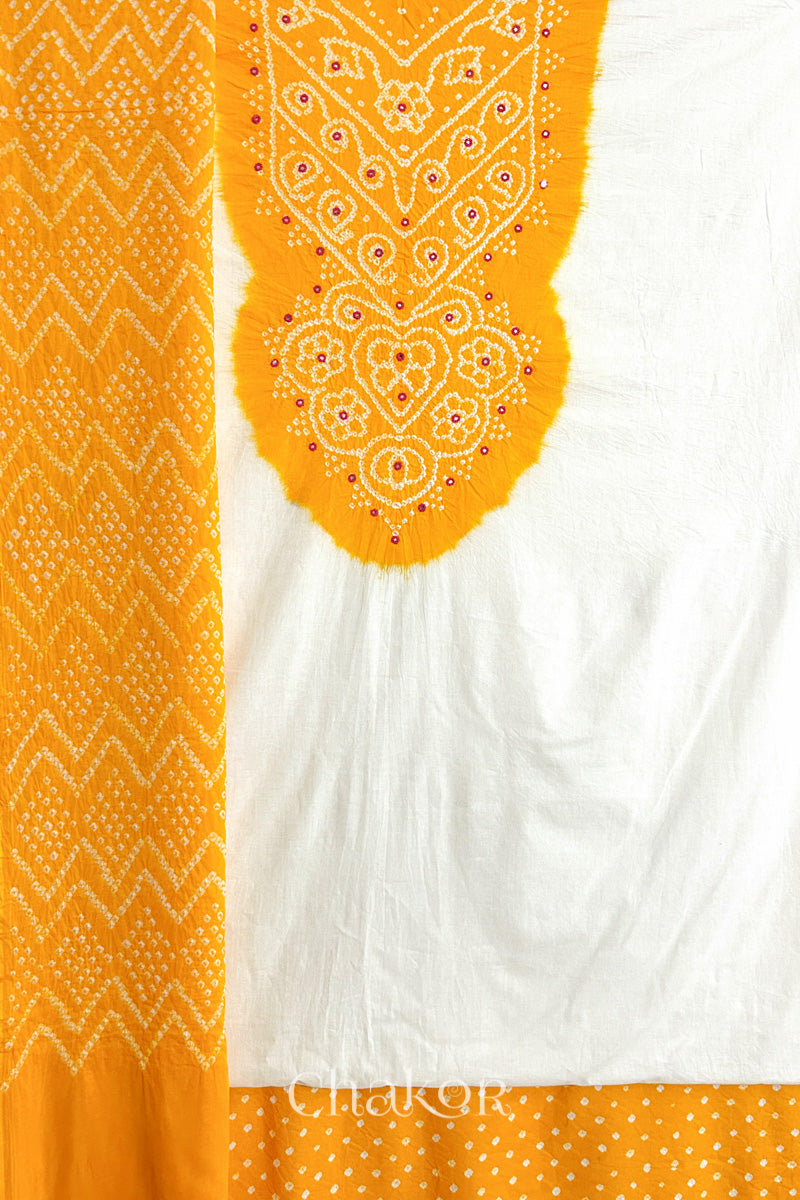 A yellow- white kurta set fabric with intricate bandhani & mirror embroidery, paired with a yellow bottom & odhani featuring a zigzag design.