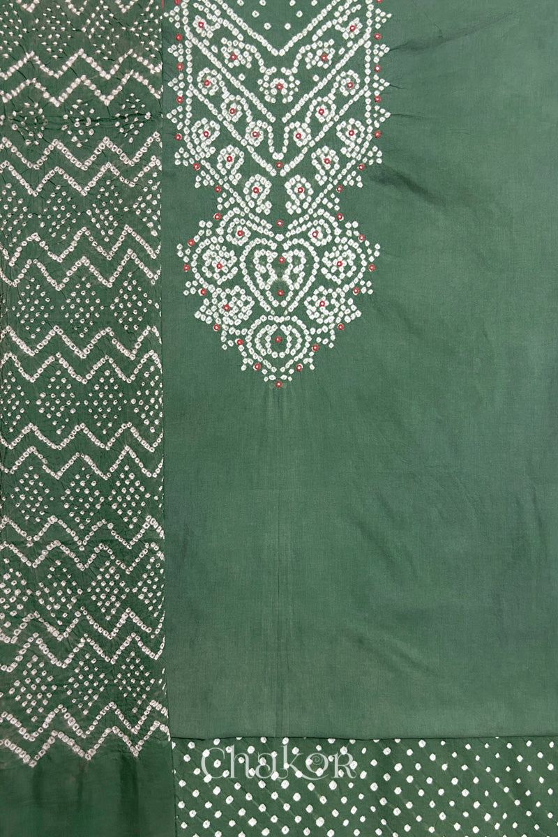 A moss green kurta set fabric with intricate bandhani & mirror embroidered yoke, paired with a matching bottom & odhani placed on the left side featuring a zigzag design.
