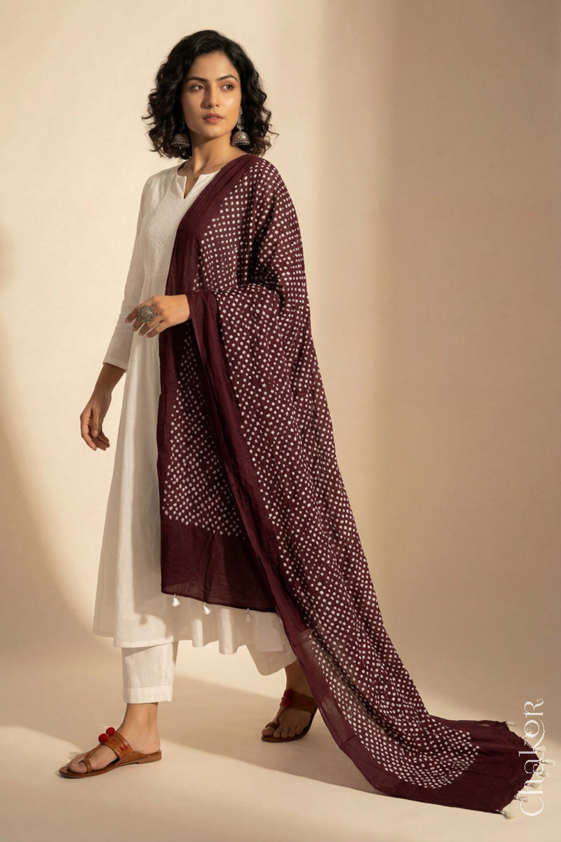 Model wearing Dark maroon Bandhani mul cotton dupatta with tie-dye dot pattern draped over a white kurta.