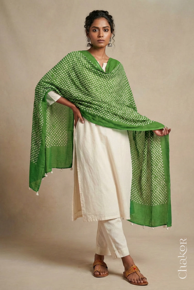 Model wearing mehendi Bandhani mul cotton dupatta with tie-dye dot pattern and pallu edged with tassels draped over a white kurta.