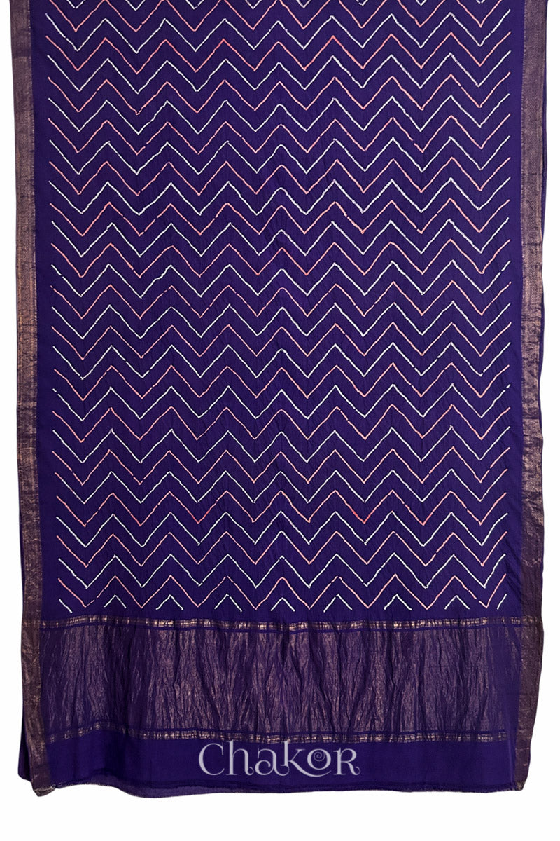 Purple saree, flat draped with Rai Bandhej zigzag pattern against white background and 'Chakor' brand watermark.