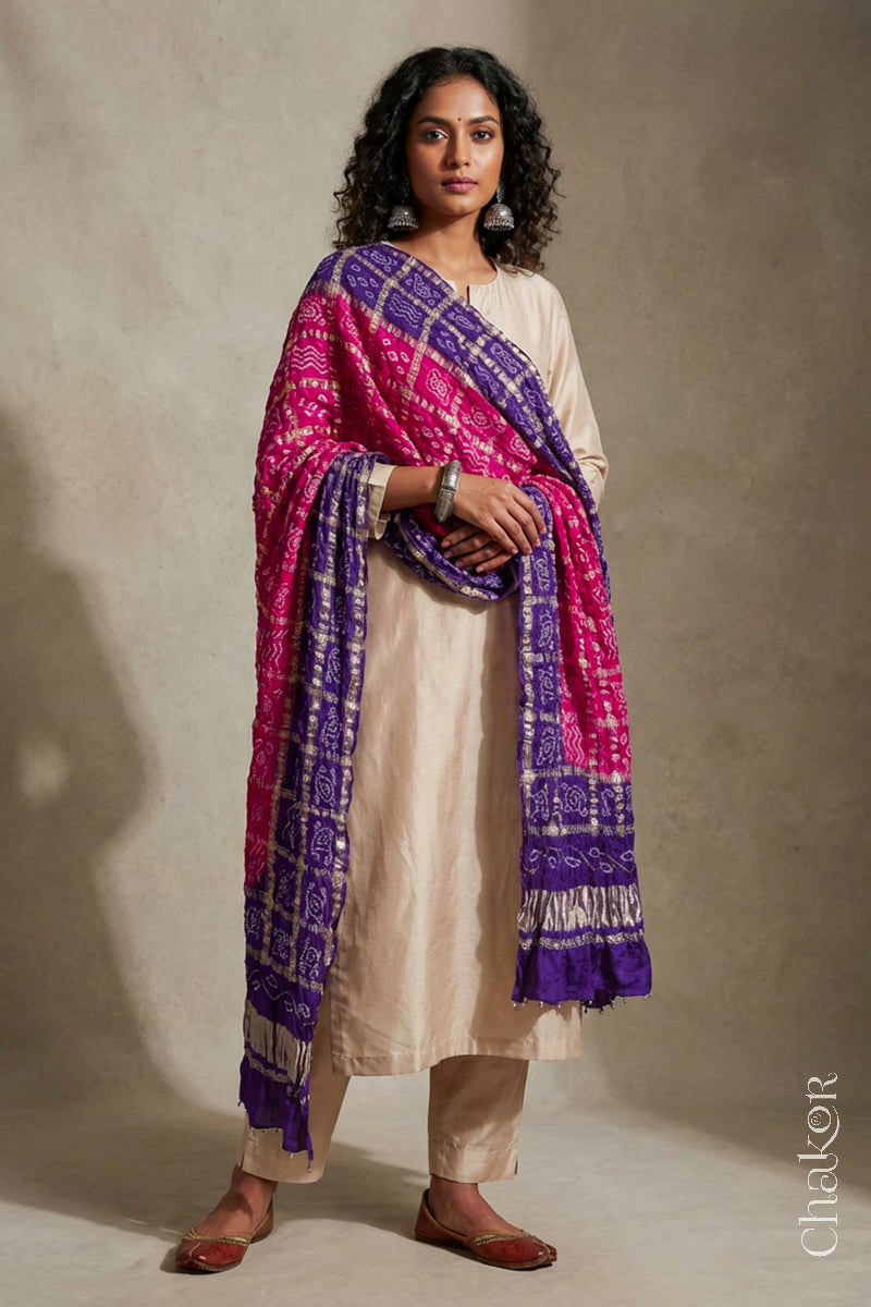 Woman wearing Pink Purple Bandhani Gharchola Gaji Silk Dupatta on beige kurta set.