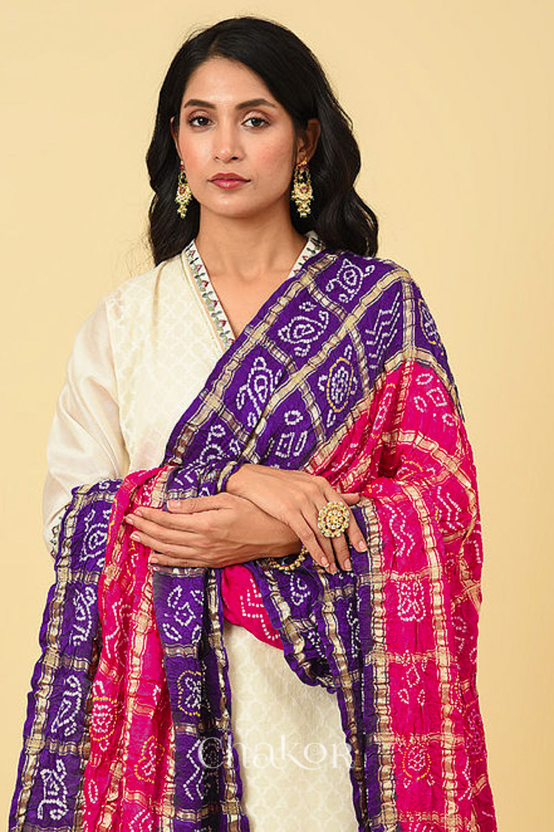 Close up of woman wearing Pink Purple Bandhani Gharchola Gaji Silk Dupatta on beige kurta set.