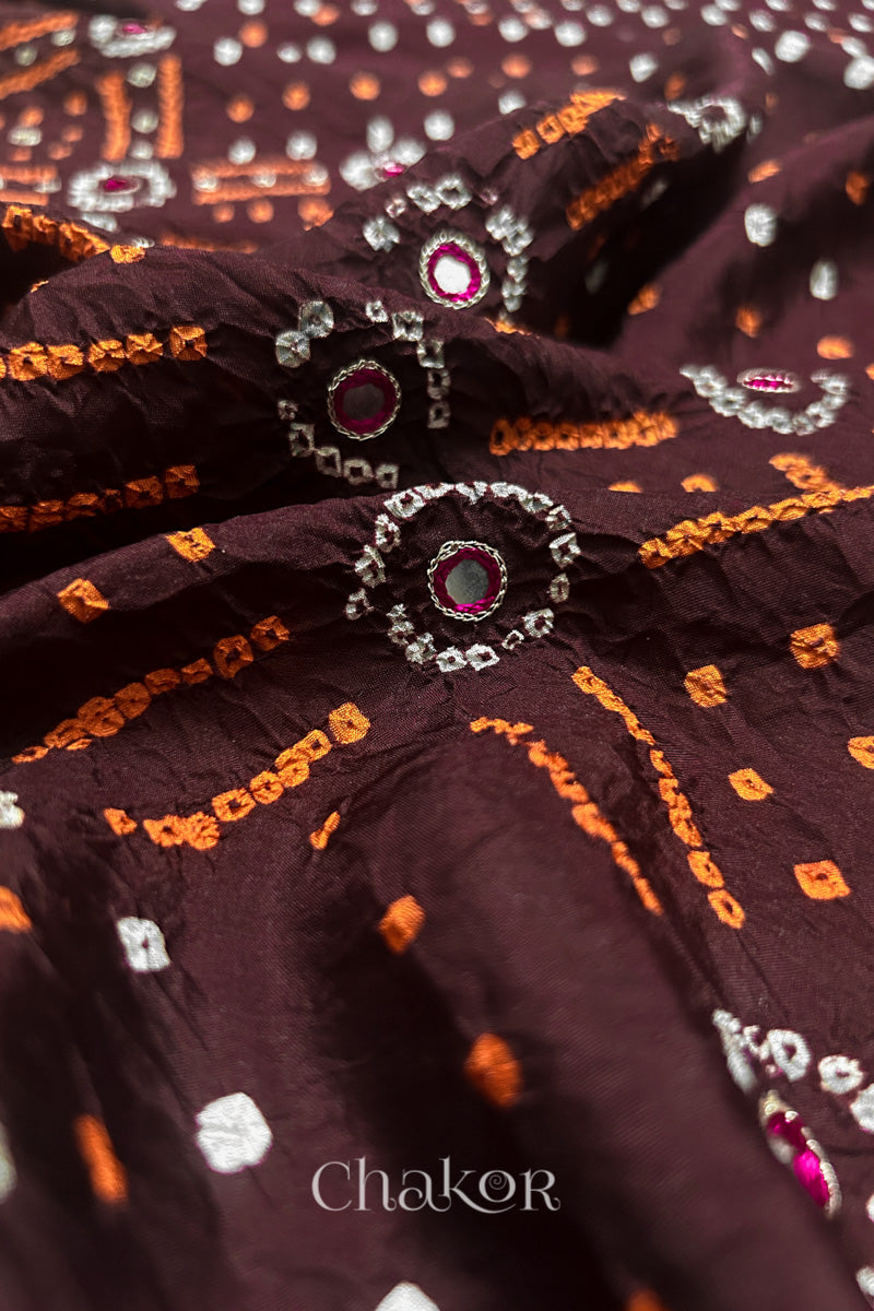 Close-up of Maroon mulberry silk Bandhani (Rai Bandhej) fabric with white and yellow  tie-dye motifs, zari embroidered pink mirror work and sequin detailing – CHAKOR.
