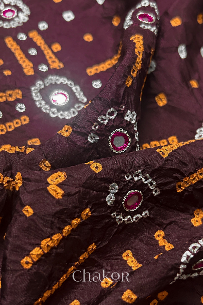 Close-up of Maroon mulberry silk Bandhani (Rai Bandhej) fabric with white and yellow  tie-dye motifs, zari embroidered pink mirror work and sequin detailing – CHAKOR.
