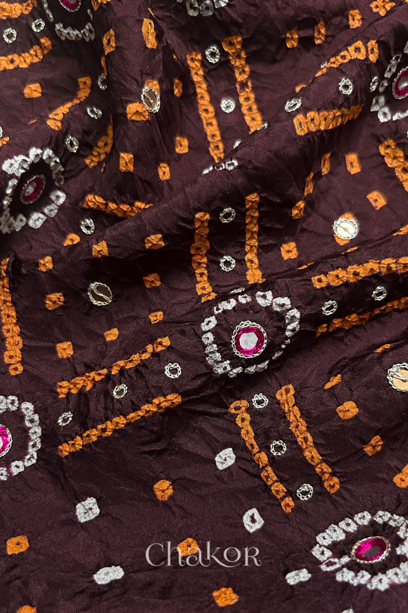 Close-up of Maroon mulberry silk Bandhani (Rai Bandhej) fabric with white and yellow  tie-dye motifs, zari embroidered pink mirror work and sequin detailing – CHAKOR.
