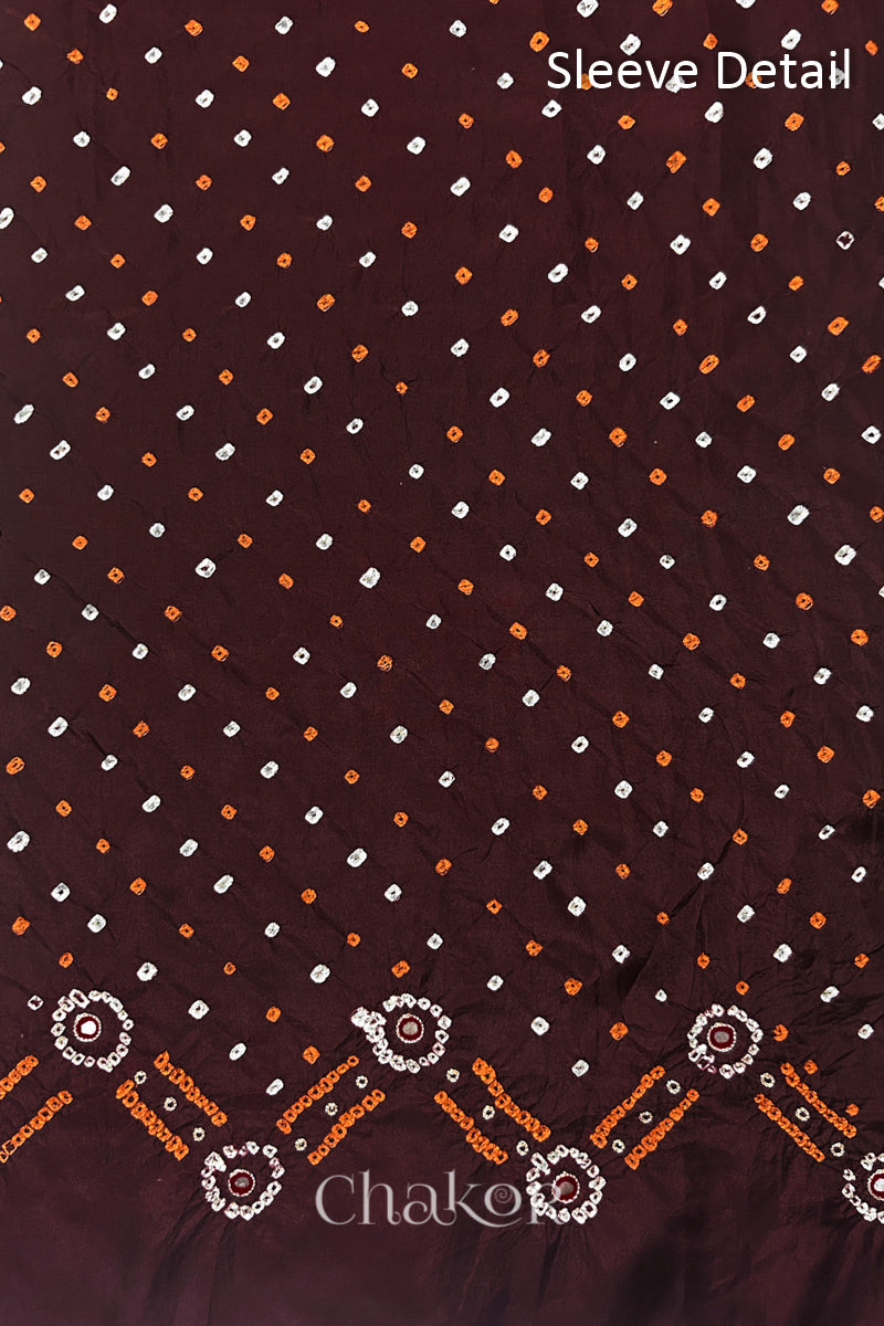 Sleeve detail of Maroon mulberry silk Bandhani (Rai Bandhej) fabric with white and yellow tie-dyed dots, traditional bandhej borders and zari embroidered pink mirror work– CHAKOR.
