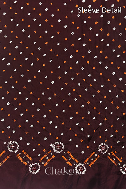 Sleeve detail of Maroon mulberry silk Bandhani (Rai Bandhej) fabric with white and yellow tie-dyed dots, traditional bandhej borders and zari embroidered pink mirror work– CHAKOR.
