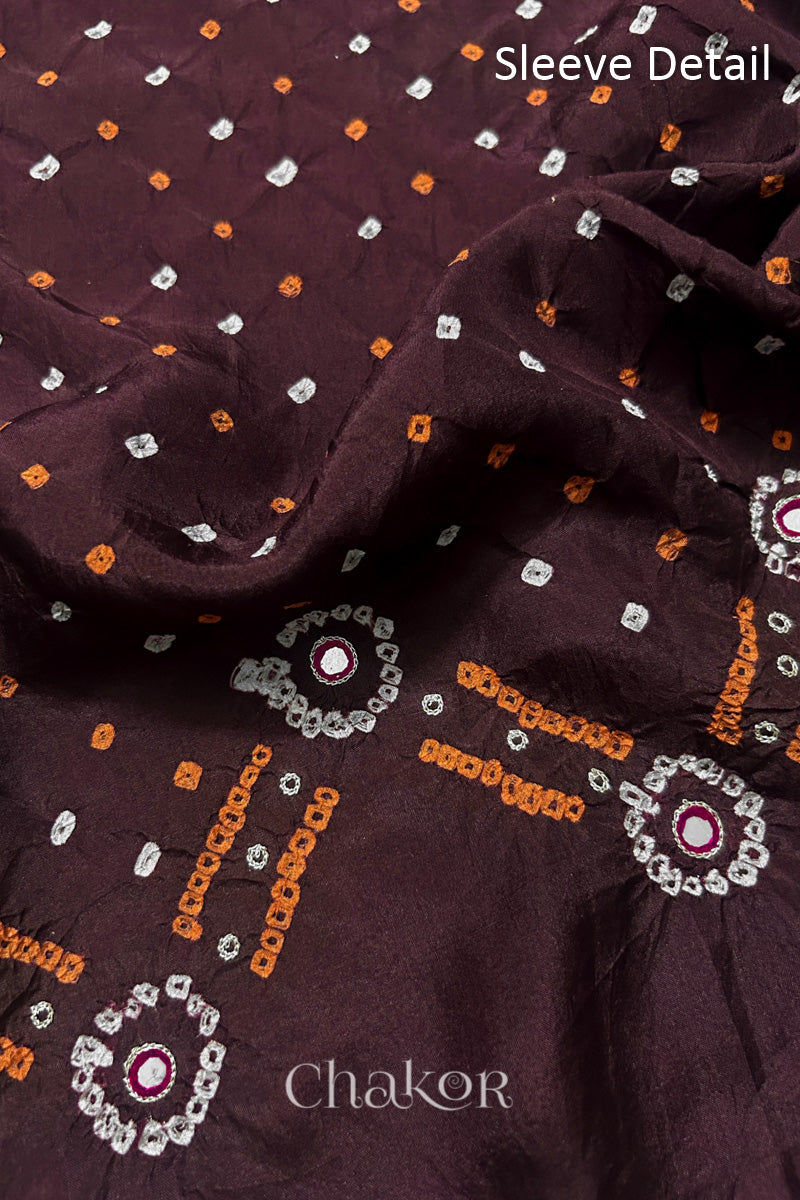 Sleeve detail of Maroon mulberry silk Bandhani (Rai Bandhej) fabric with white and yellow tie-dyed dots, traditional bandhej borders and zari embroidered pink mirror work– CHAKOR.
