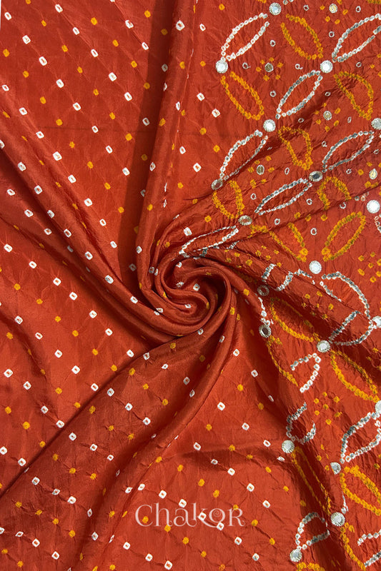 Rusty Orange mulberry silk Bandhani (Rai Bandhej) fabric with white tie-dyed motifs, golden zari mirror and sequin embellishment, arranged in a swirling design  – CHAKOR.
