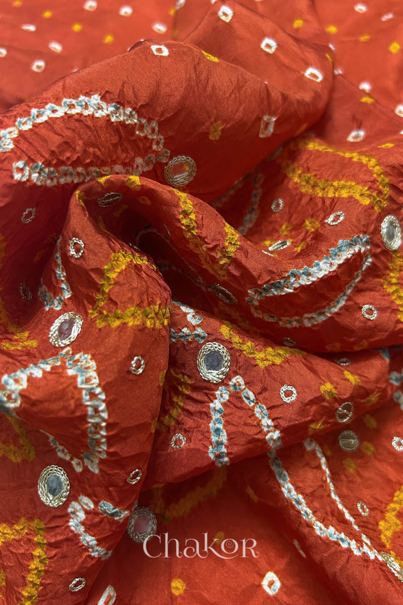Close-up of Rusty Orange mulberry silk Bandhani (Rai Bandhej) fabric with white tie-dye motifs, golden zari embroidered golden zari mirror work and sequin detailing – CHAKOR.
