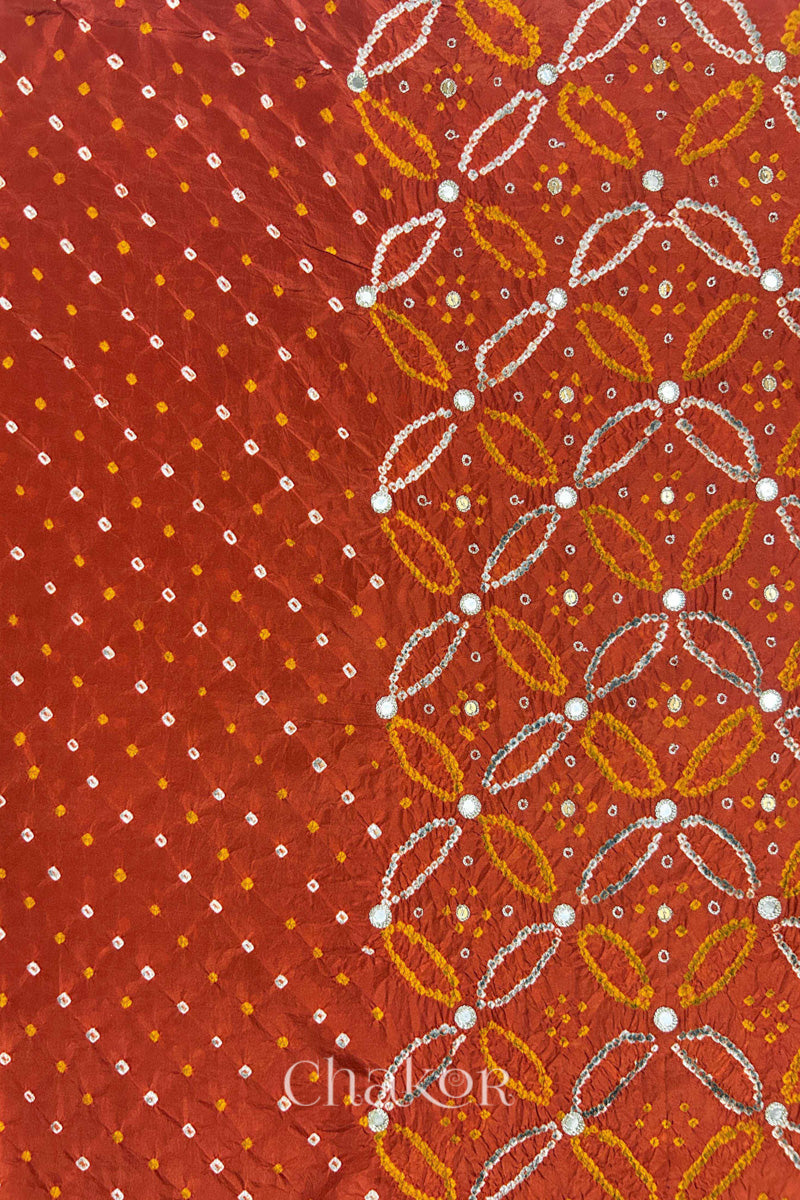 Rusty Orange mulberry silk Bandhani (Rai Bandhej) fabric showing full layout with white tie-dye dots, floral bandhej pattern, and golden zari mirror & sequins embroidery – CHAKOR.
