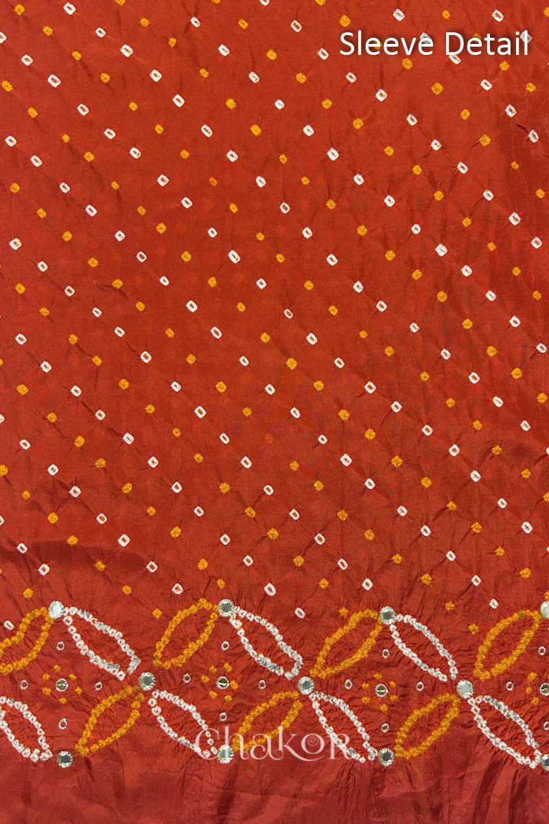 Sleeve detail of Rusty Orange mulberry silk Bandhani (Rai Bandhej) fabric with white dots, floral bandhej borders and golden zari mirror embroidery – CHAKOR.
