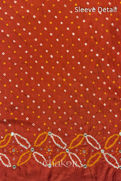 Sleeve detail of Rusty Orange mulberry silk Bandhani (Rai Bandhej) fabric with white dots, floral bandhej borders and golden zari mirror embroidery – CHAKOR.
