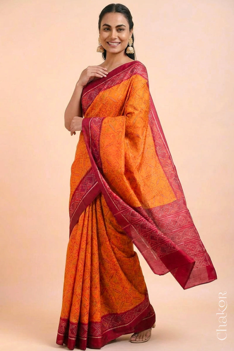 Model wearing Handloom Orange Rajkoti Patola Ikat Mulberry Silk Saree with red borders pallu, woven using traditional designs in Gujarat.