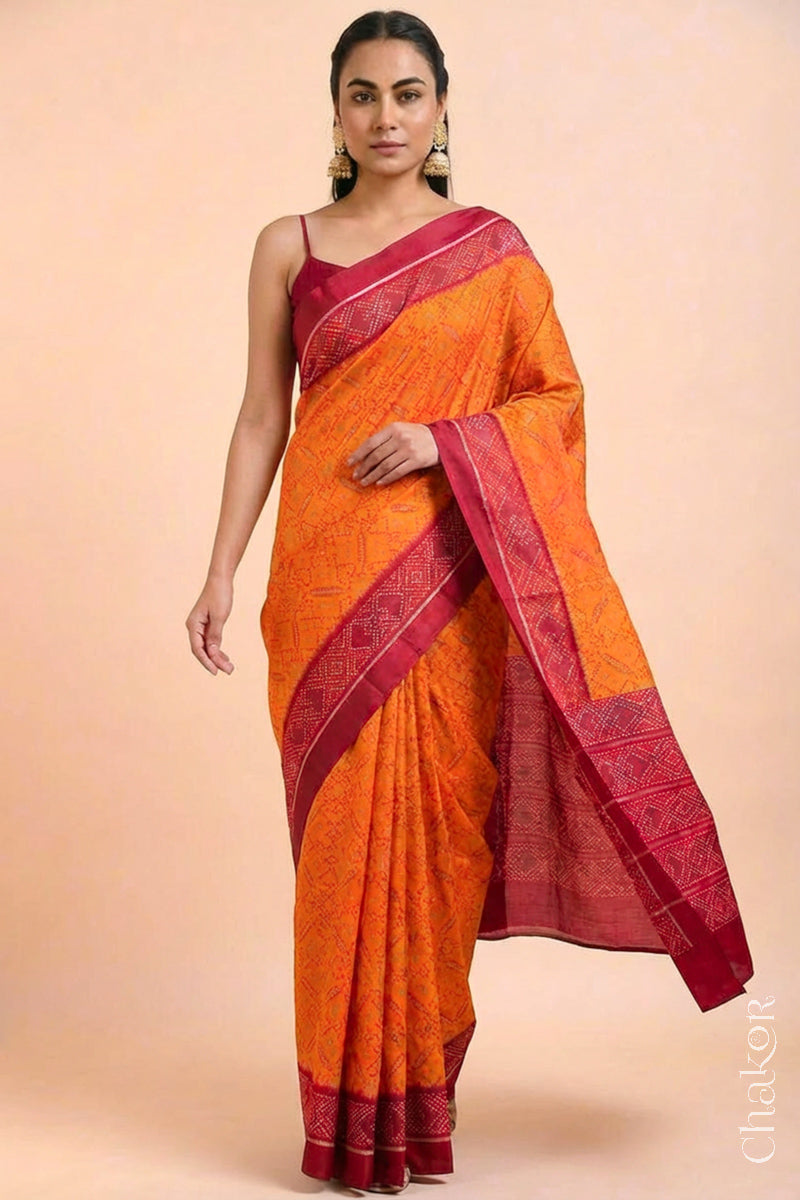 Model wearing Handloom Orange Rajkoti Patola Ikat Mulberry Silk Saree with red borders pallu, woven using traditional designs in Gujarat.