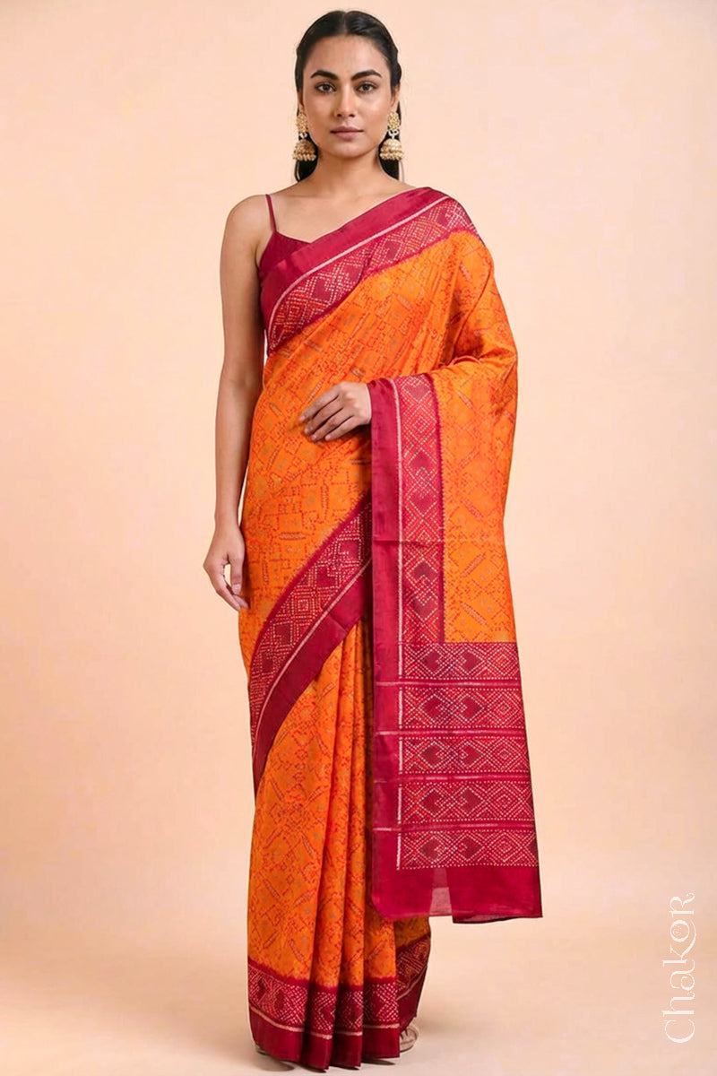 Model wearing Handloom Orange Rajkoti Patola Ikat Mulberry Silk Saree with red borders pallu, woven using traditional designs in Gujarat.