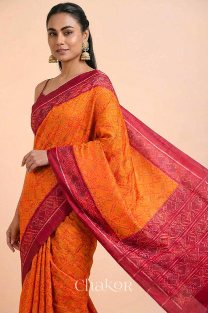 Model wearing Handloom Orange Rajkoti Patola Ikat Mulberry Silk Saree with red borders pallu, woven using traditional designs in Gujarat.