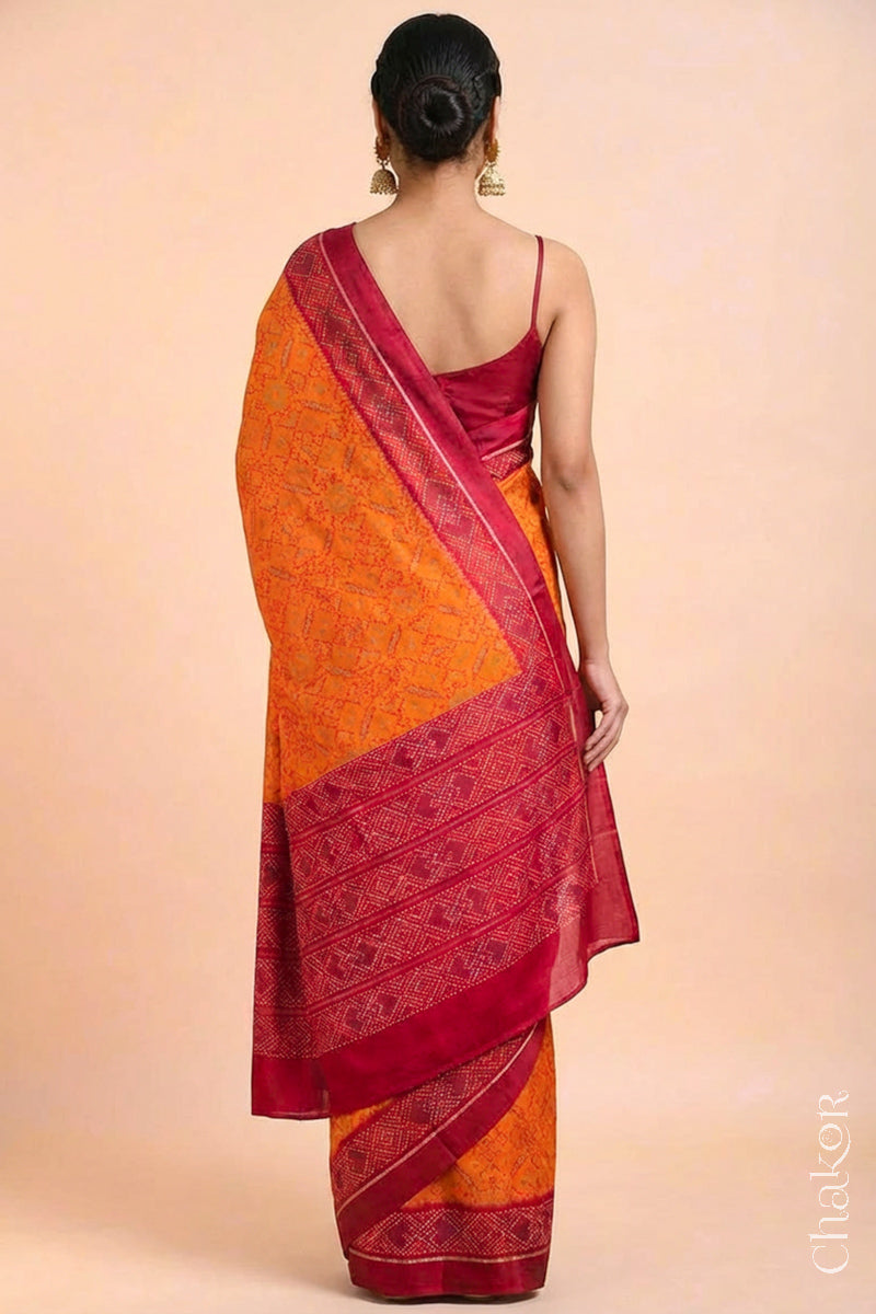 Model wearing Handloom Orange Rajkoti Patola Ikat Mulberry Silk Saree with red borders pallu, woven using traditional designs in Gujarat.