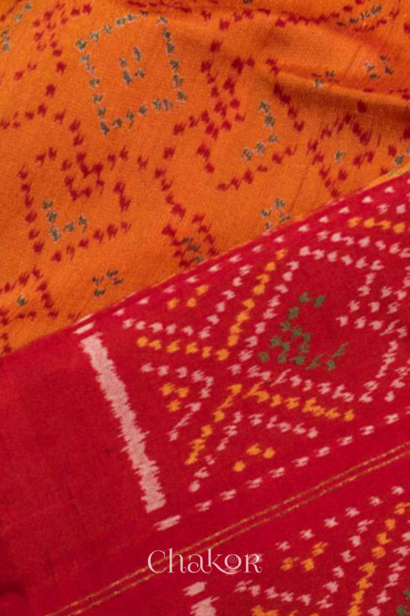 Close up of Handloom Orange Rajkoti Patola Ikat Mulberry Silk Saree with red borders pallu, woven using traditional designs in Gujarat.