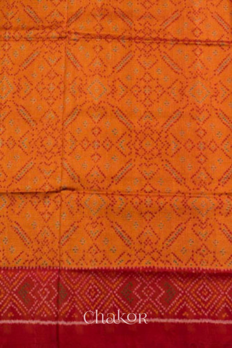 Close up of Handloom Orange Rajkoti Patola Ikat Mulberry Silk Saree with red borders pallu, woven using traditional designs in Gujarat.