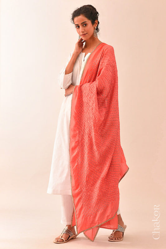 Woman wearing peach Bandhani mulberry silk dupatta with tie-dye dot pattern & detailed with golden lace.