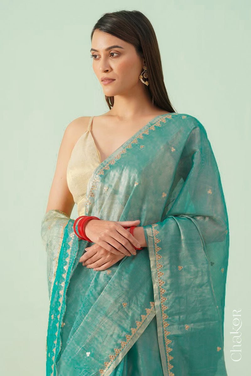 Model in peacock blue Chanderi tissue silk cotton saree showing embroidered border and woven texture.
