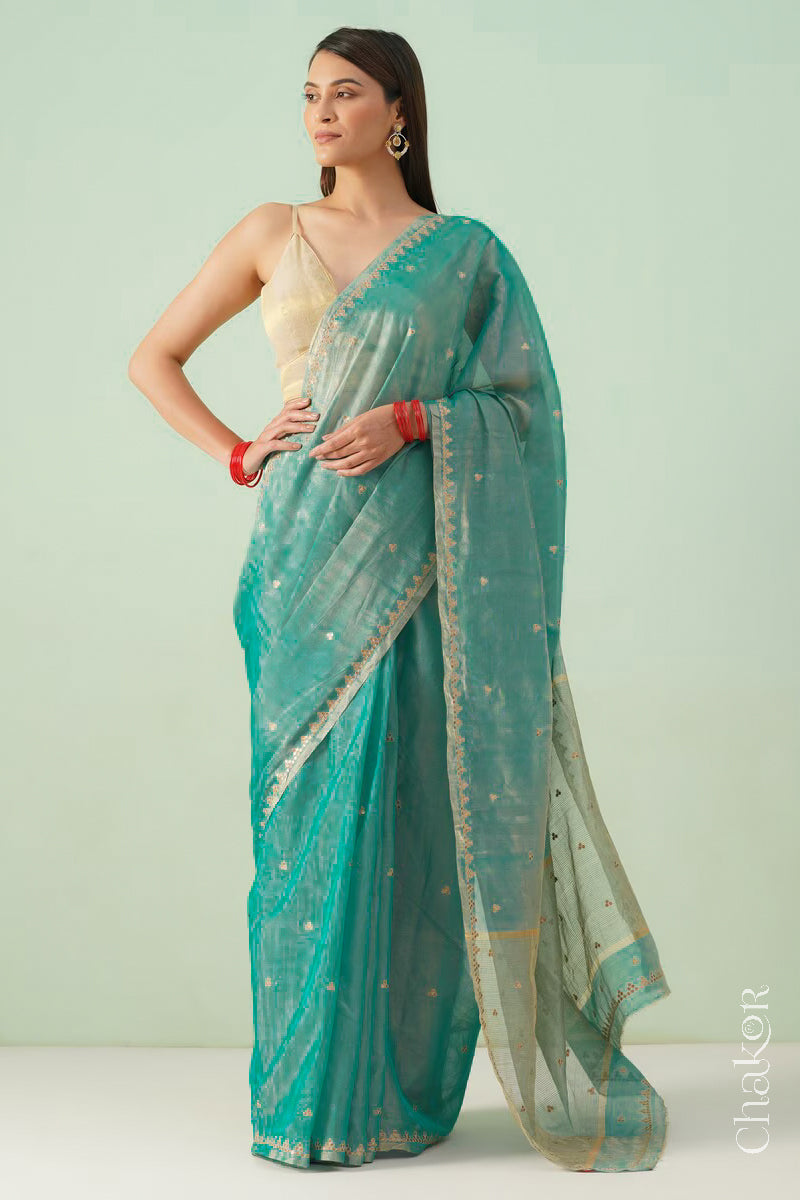 Full view of model dressed in peacock blue Chanderi tissue silk cotton saree draped to display sequin tikki embroidery.
