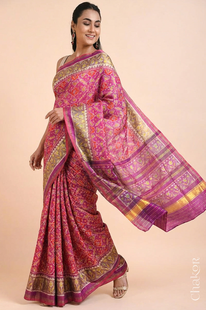Model wearing Handloom Pink Rajkoti Patola Ikat Mulberry Silk Saree with tissue borders, and mauve pallu woven using traditional designs in Gujarat.