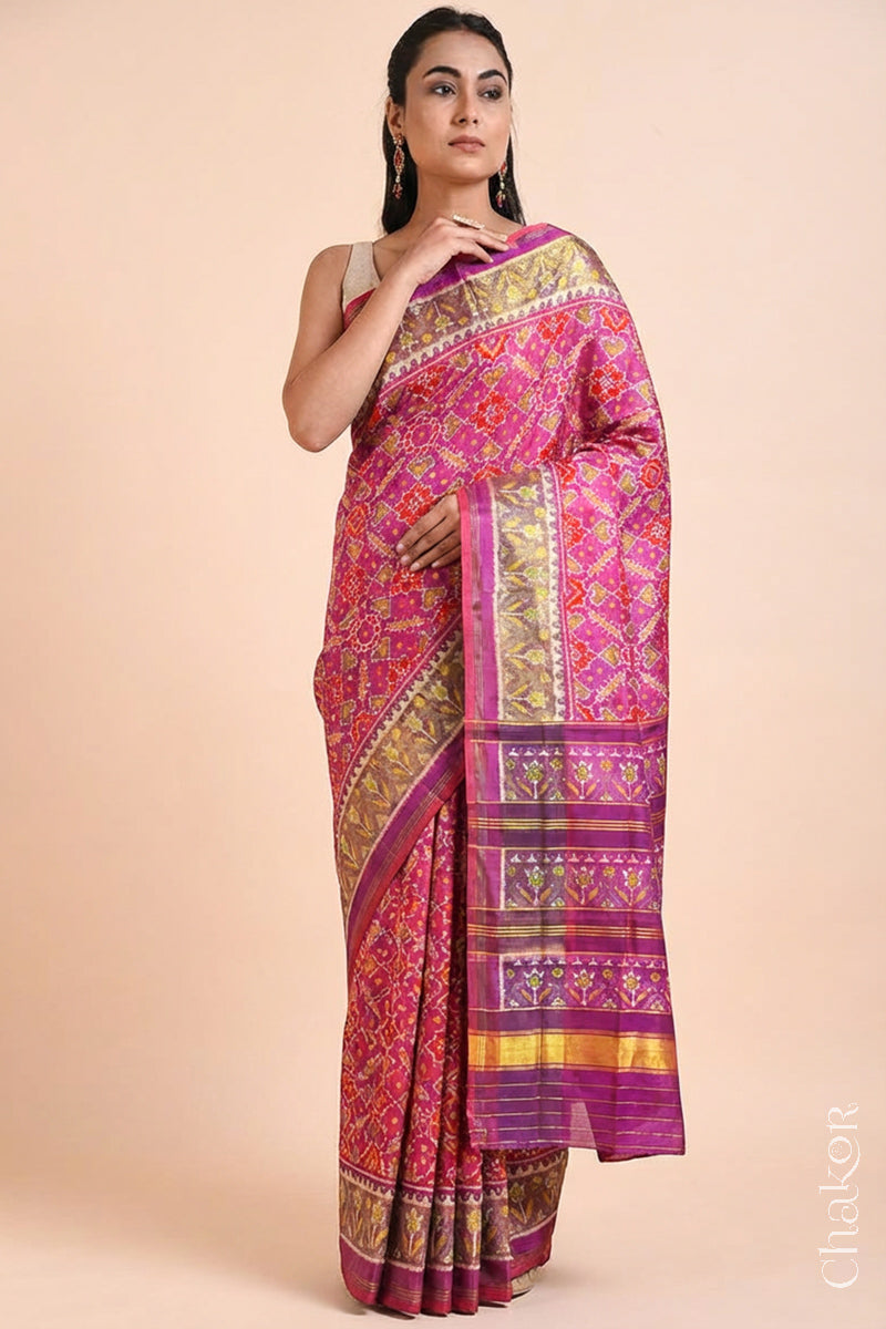 Model wearing Handloom Pink Rajkoti Patola Ikat Mulberry Silk Saree with tissue borders, and mauve pallu woven using traditional designs in Gujarat.