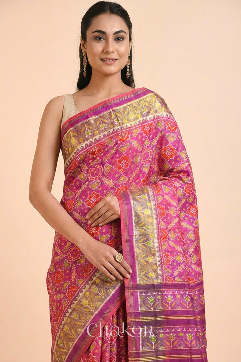 Model wearing Handloom Pink Rajkoti Patola Ikat Mulberry Silk Saree with tissue borders, and mauve pallu woven using traditional designs in Gujarat.