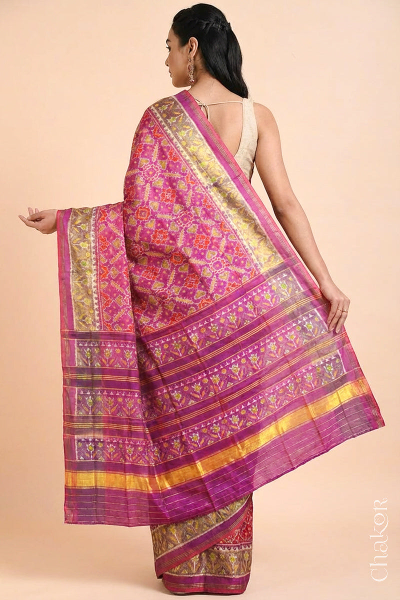 Model wearing Handloom Pink Rajkoti Patola Ikat Mulberry Silk Saree with tissue borders, and mauve pallu woven using traditional designs in Gujarat.