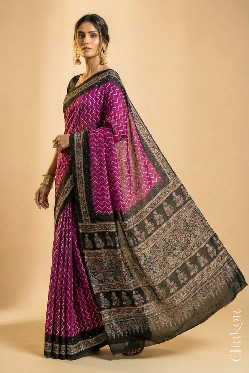 Woman wearing Magenta Bandhani Saree with Black Ajrakh printed border and pallu in pure gaji silk with traditional bandhej tie-dye & mirror work, handcrafted in Kutch. 