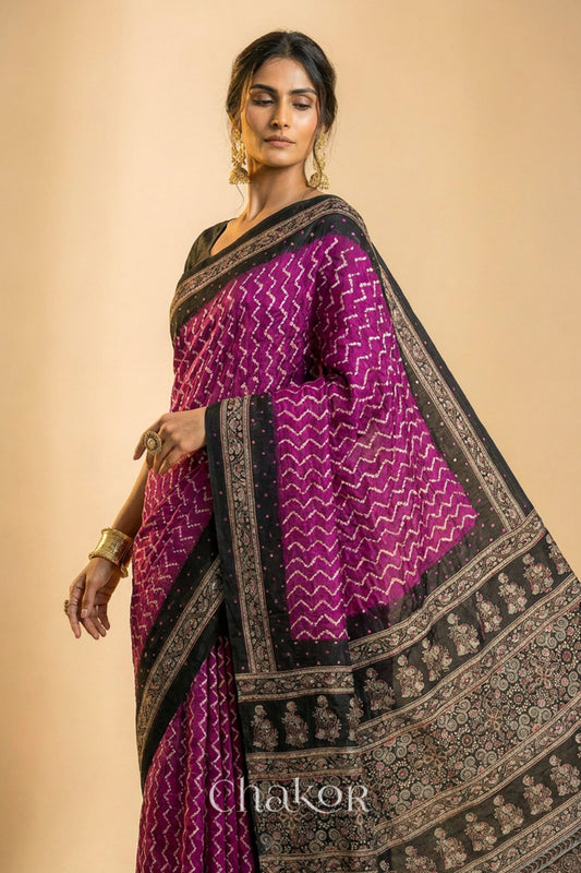 Woman wearing Magenta Bandhani Saree with Black Ajrakh printed border and pallu in pure gaji silk with traditional bandhej tie-dye & mirror work, handcrafted in Kutch. 