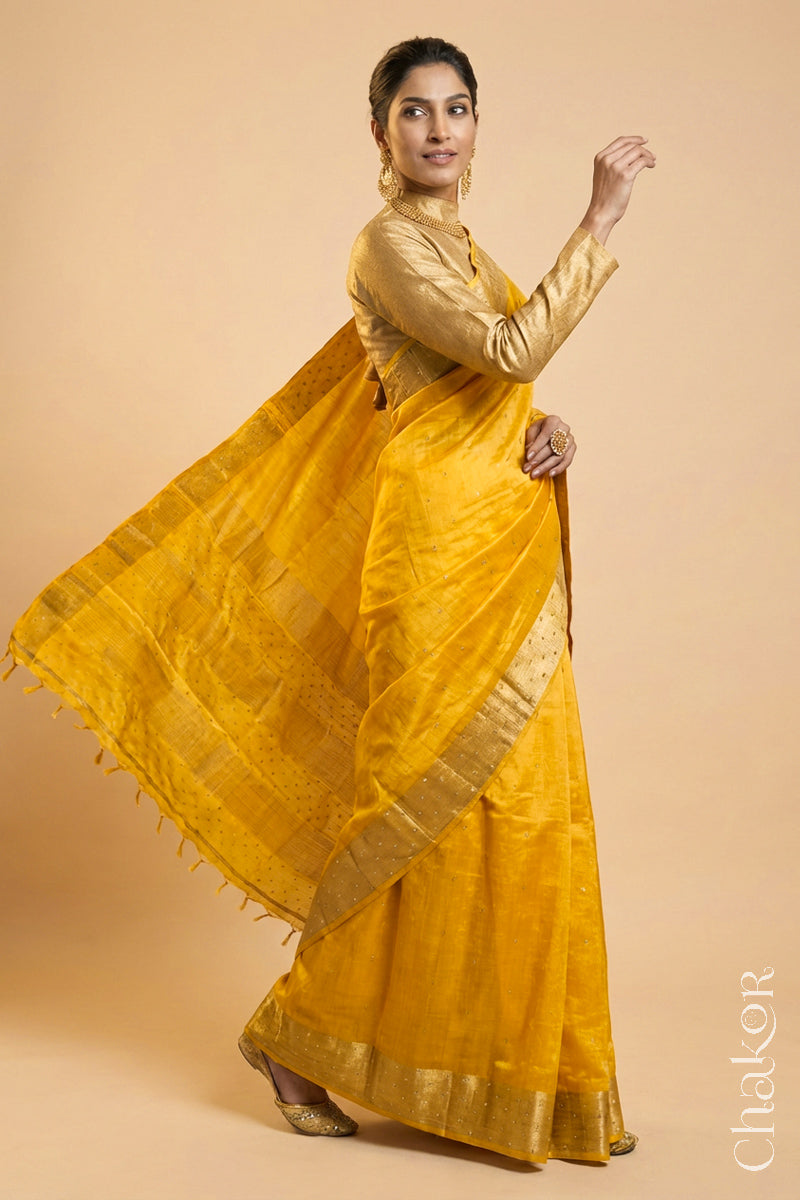 Woman wearing a Yellow tussar silk handloom saree with golden zari border & hand embroidered with  sequins & zari work