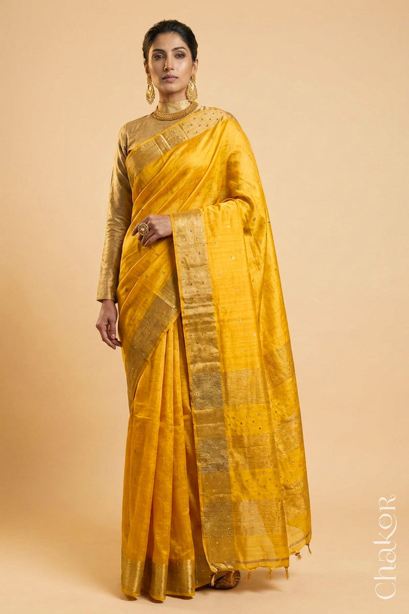 Woman wearing a Yellow tussar silk handloom saree with golden zari border & hand embroidered with  sequins & zari work