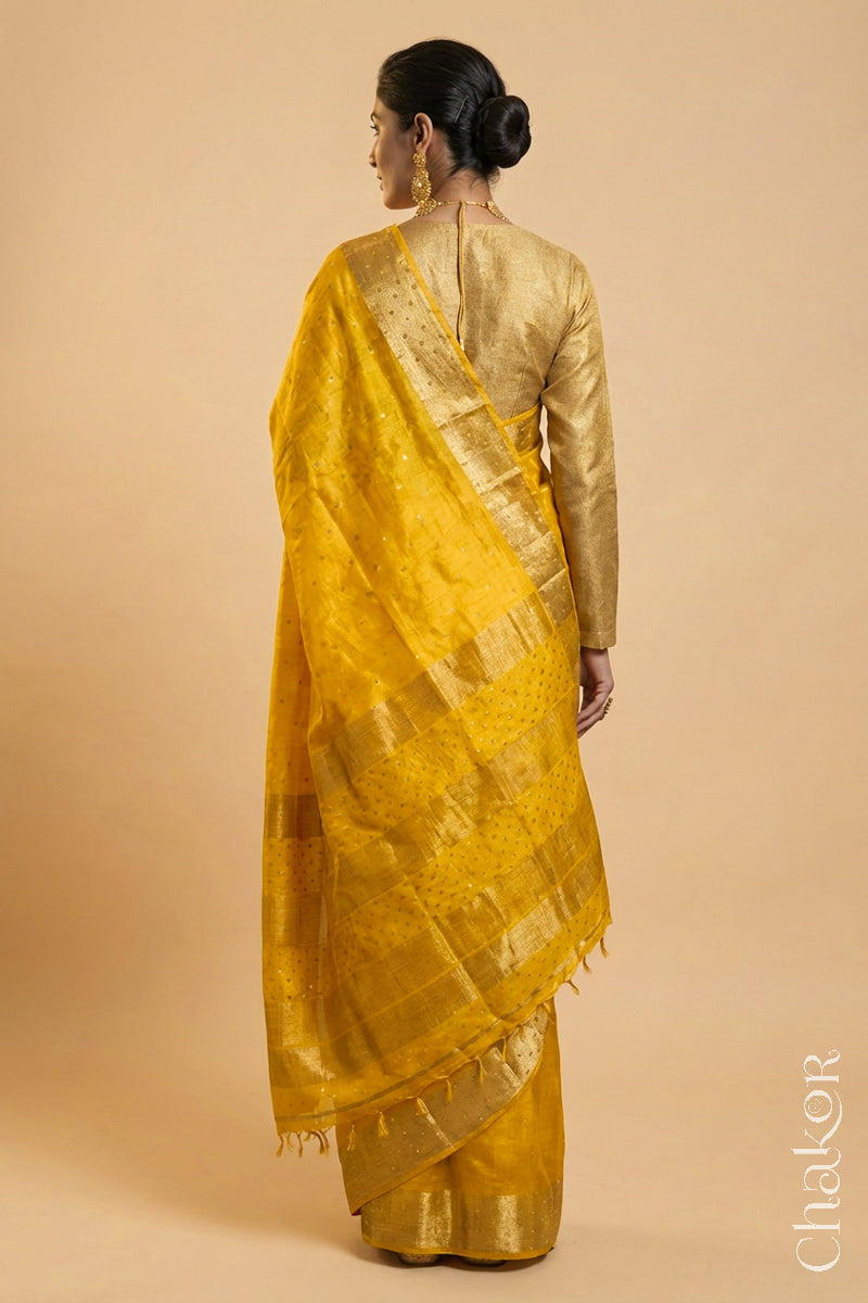 Back Pose of Woman wearing a Yellow tussar silk handloom saree with golden zari border & hand embroidered with  sequins & zari work