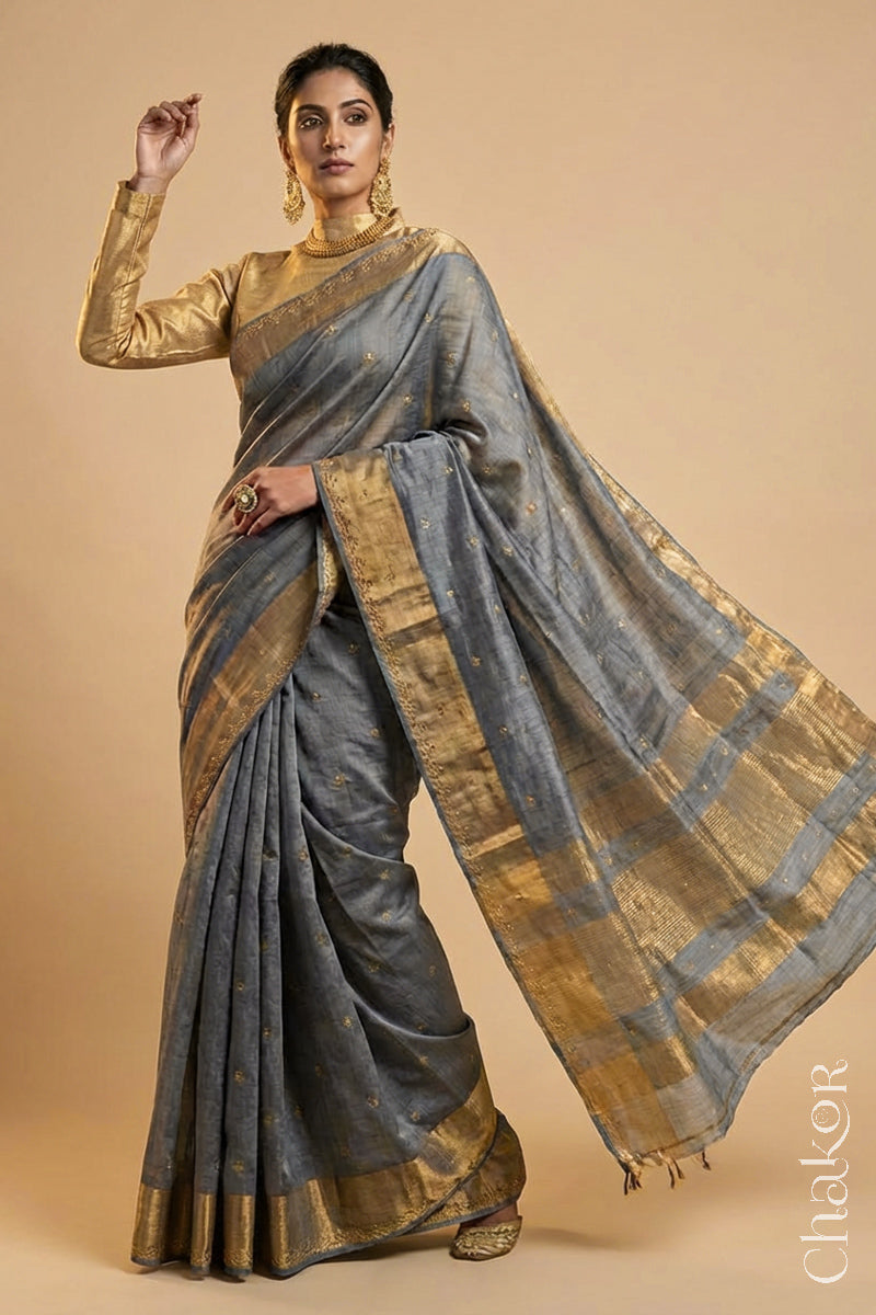 Woman wearing a Grey tussar silk handloom saree with golden zari border & hand embroidered with  sequins & zari work