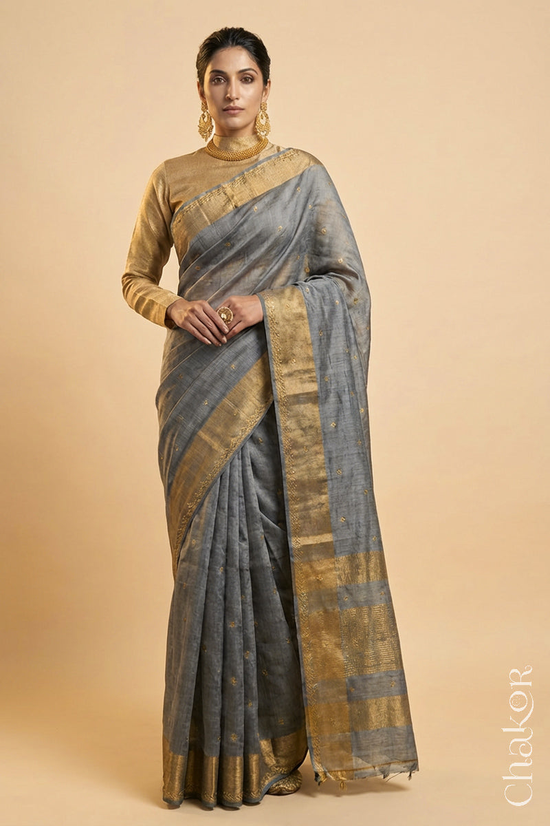 Woman wearing a Grey tussar silk handloom saree with golden zari border & hand embroidered with  sequins & zari work