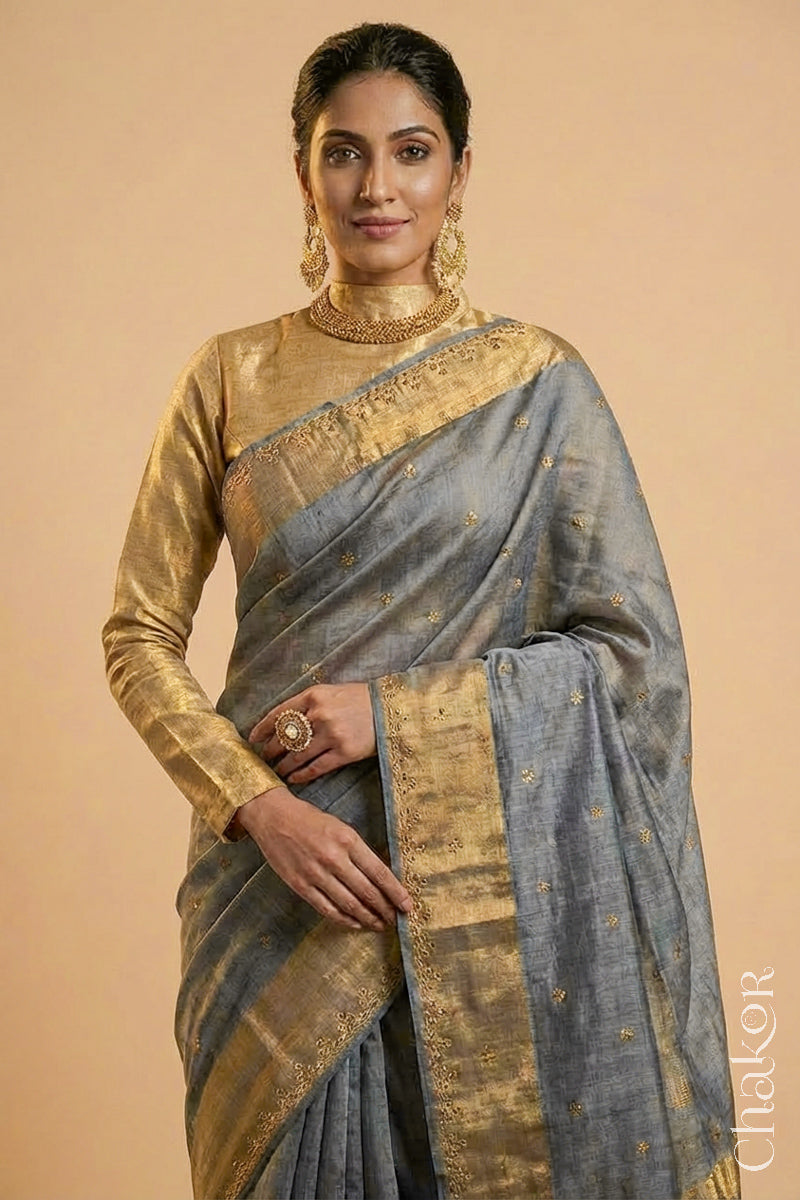 Woman wearing a Grey tussar silk handloom saree with golden zari border & hand embroidered with  sequins & zari work