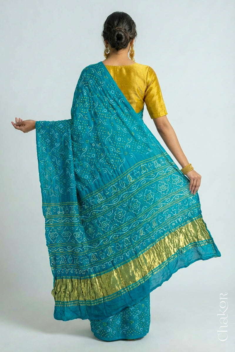 Woman wearing Hancrafted Peacock Blue Bandhani Gaji Silk Saree, with traditional rai bandhej patterns and mukaish embroidery.