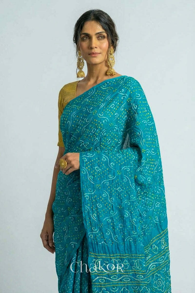 Woman wearing Hancrafted Peacock Blue Bandhani Gaji Silk Saree, with traditional rai bandhej patterns and mukaish embroidery.