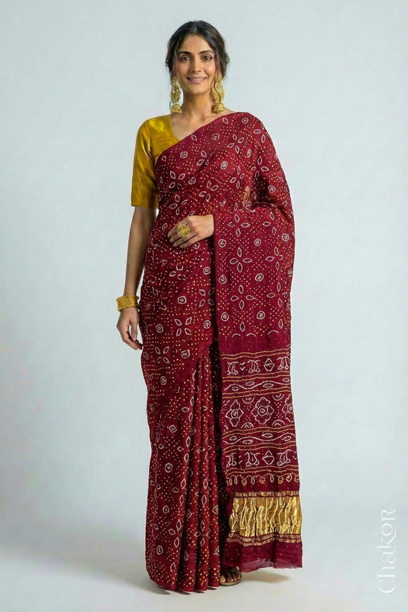 Model wearing Handcrafted Maroon Bandhani Gaji Silk Saree with traditional rai bandhej patterns and mukaish embroidery.