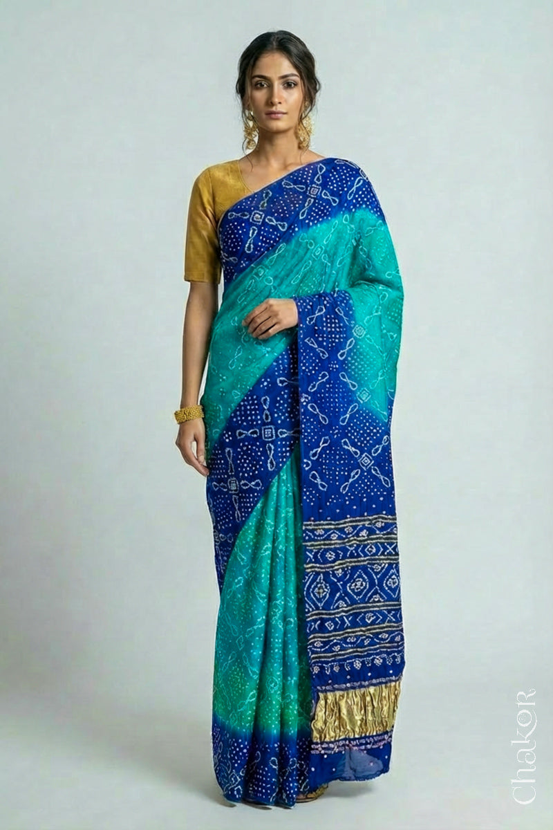 Model wearing Handcrafted Peacock Blue Ombre Bandhani Gaji Silk Saree with rai bandhej patterns and mirror, sequins embroidery.